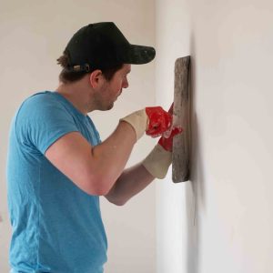 Home improvement concept. Handyman worker with putty knife working on apartment wall filling
